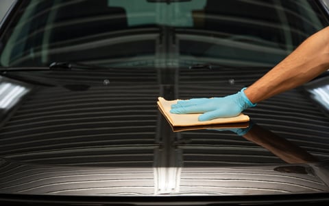A man applying car wax to give a shiny finish to the vehicle