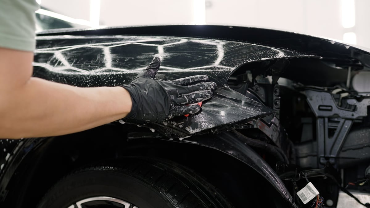 Car detailer cleaning vehicle with sponge and detergent during exterior detailing process