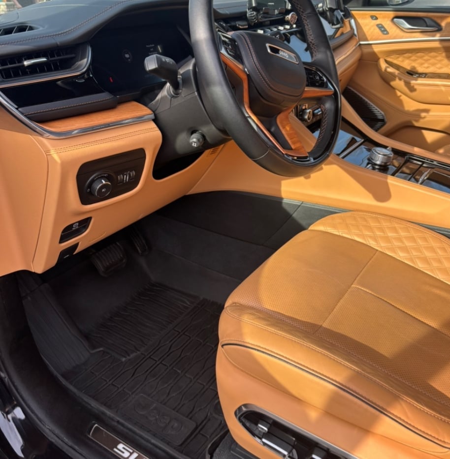 Luxury car interior with tan leather seats, black steering wheel, and black floor mats