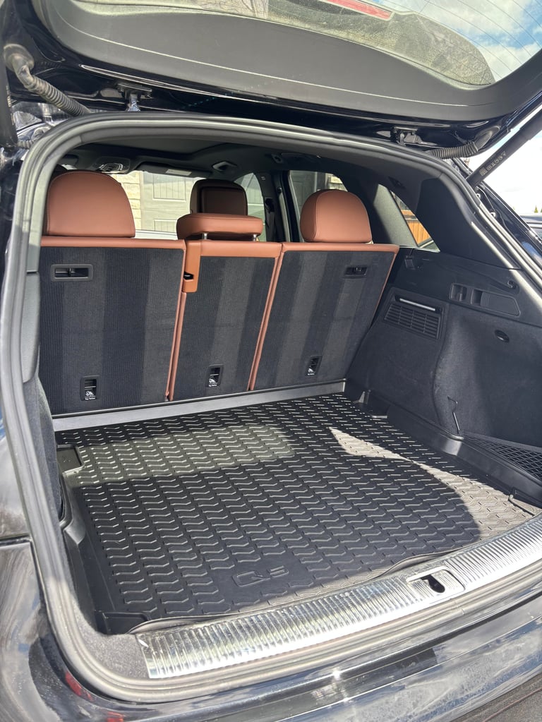 Open car trunk with rubber cargo mat, orange and black rear seats visible, tailgate open